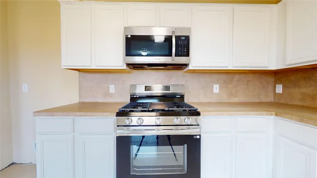 a kitchen with stainless steel appliances a stove a microwave and cabinets