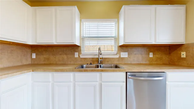 a kitchen with stainless steel appliances granite countertop a sink and a white cabinets