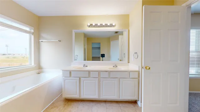 a spacious bathroom with a tub sink and mirror