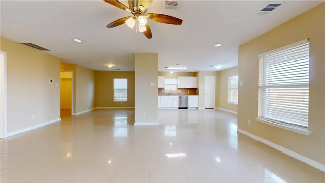 a view of an empty room and kitchen view