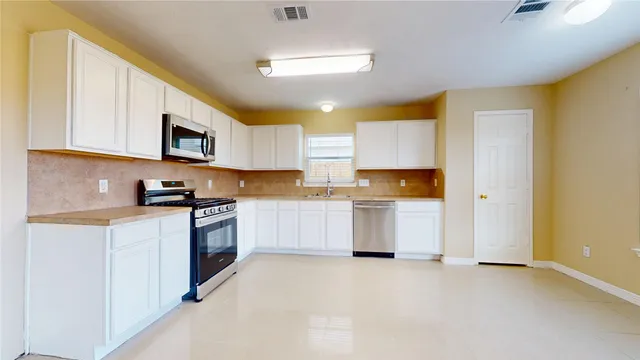 a kitchen with stainless steel appliances granite countertop a stove a sink dishwasher and a refrigerator