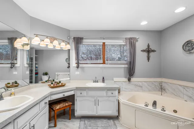 a bathroom with a tub a sink double vanity and mirror