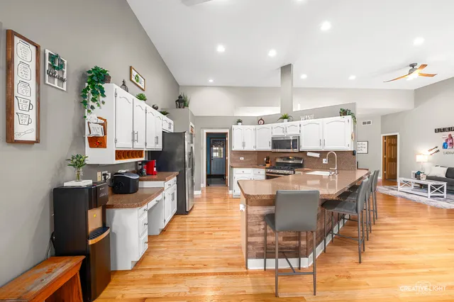 a kitchen with stainless steel appliances kitchen island granite countertop a stove top oven a sink a dining table and chairs