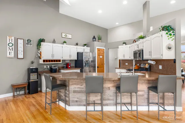 a kitchen with stainless steel appliances kitchen island granite countertop a dining table chairs and a refrigerator