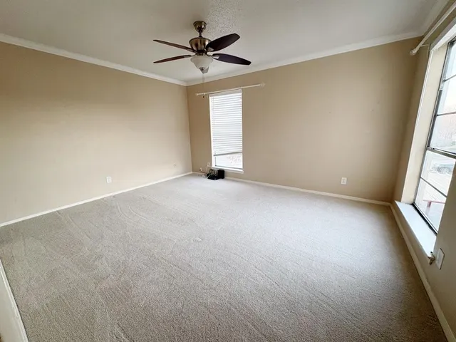 an empty room with windows and view of kitchen