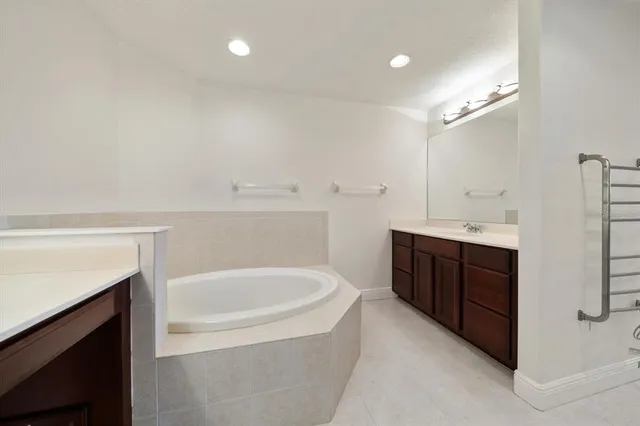 a spacious bathroom with a double vanity sink a mirror and a bathtub