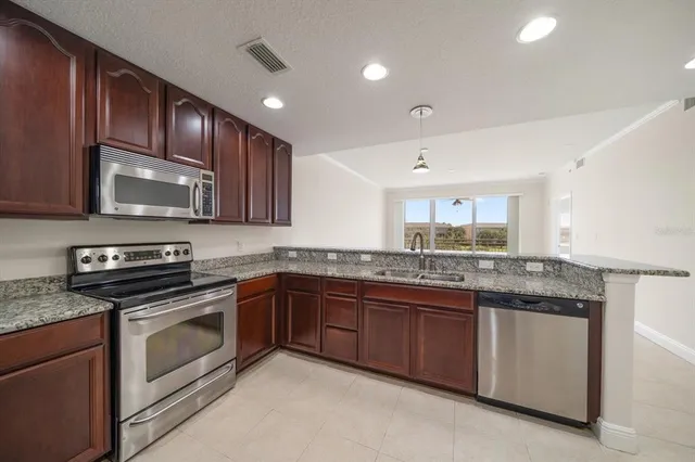 a kitchen with stainless steel appliances granite countertop wooden cabinets granite counter tops and a stove