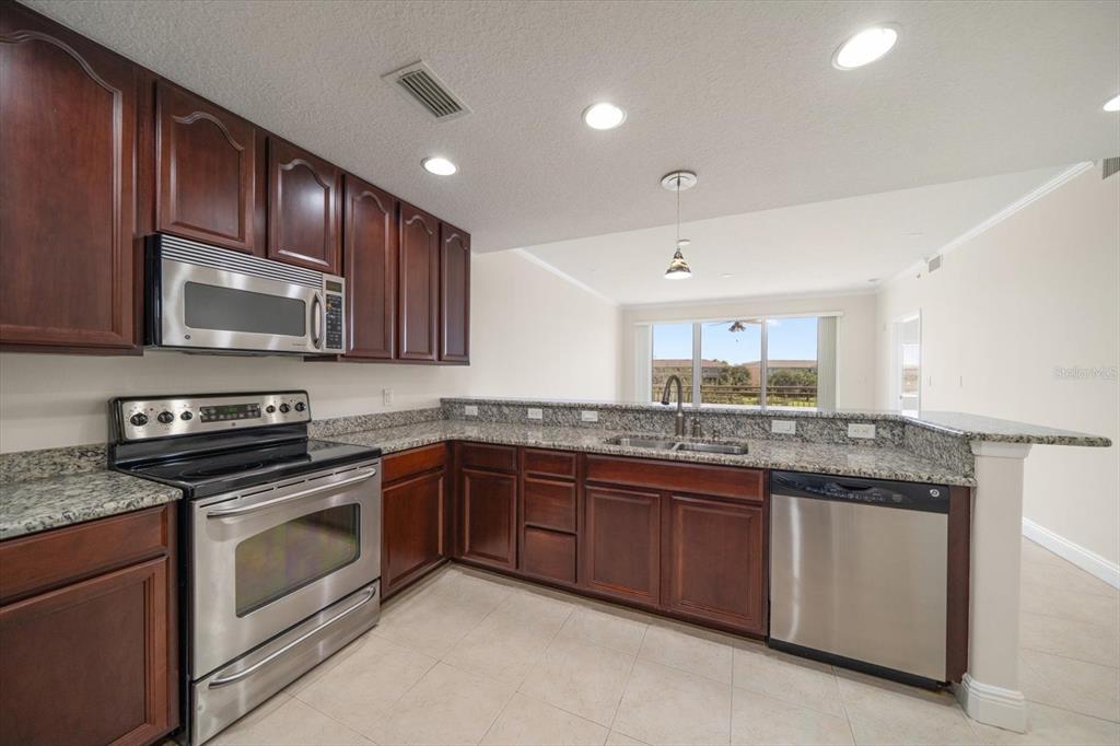 7069 Key Haven Road, Unit 304 Seminole, FL 33777 - Photo 5 of 50 a kitchen with stainless steel appliances granite countertop wooden cabinets granite counter tops and a stove