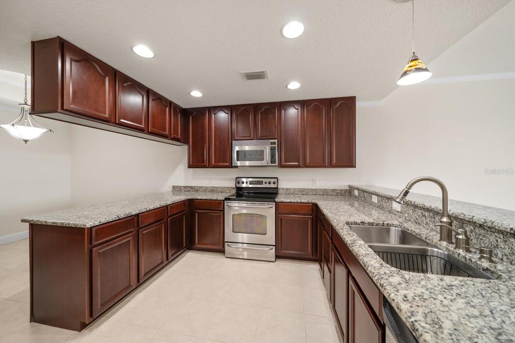 7069 Key Haven Road, Unit 304 Seminole, FL 33777 - Photo 8 of 50 a kitchen with stainless steel appliances granite countertop a sink stove and cabinets