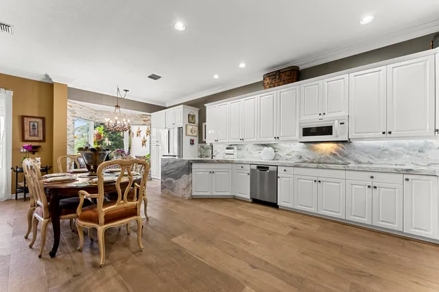 a kitchen with granite countertop white cabinets a counter top space and stainless steel appliances