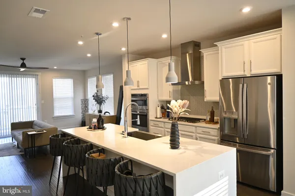 a kitchen with stainless steel appliances kitchen island granite countertop a refrigerator and a sink