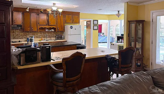 a kitchen with stainless steel appliances kitchen island granite countertop a refrigerator a stove top oven and a dining table with wooden floor