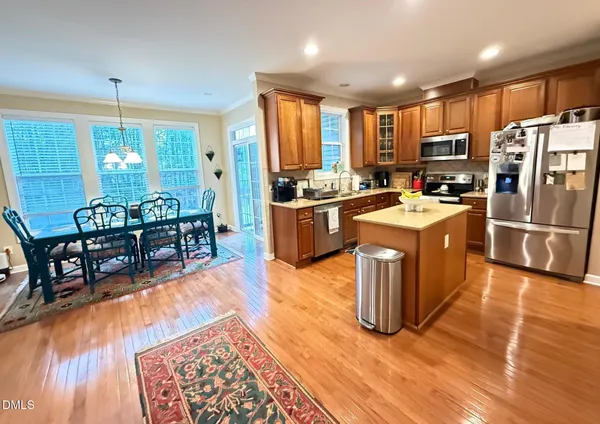 a kitchen with stainless steel appliances granite countertop a refrigerator a stove top oven a sink dishwasher and chairs with wooden floor