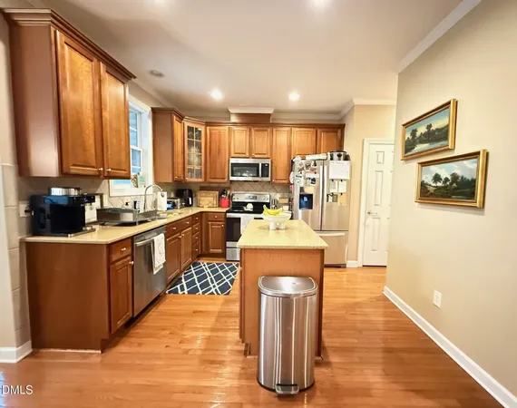 a kitchen with stainless steel appliances kitchen island granite countertop a stove a sink a refrigerator and blue cabinets with wooden floor