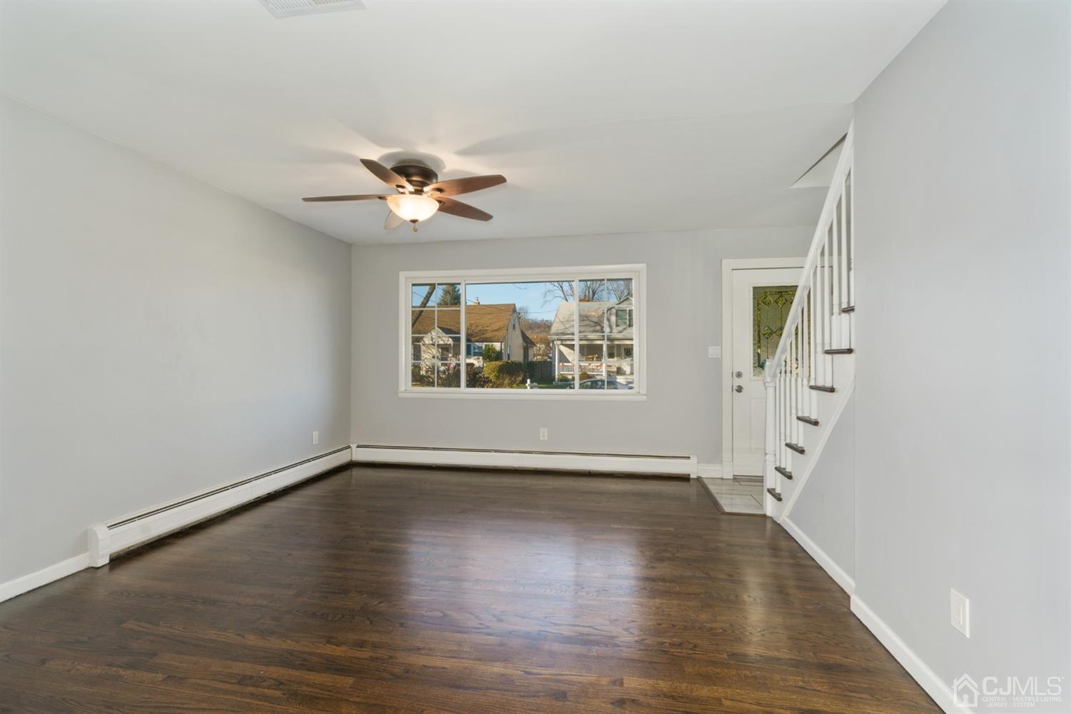 403 Fulton Street Middlesex, NJ 08846 - Photo 8 of 31 an empty room with wooden floor chandelier fan and windows
