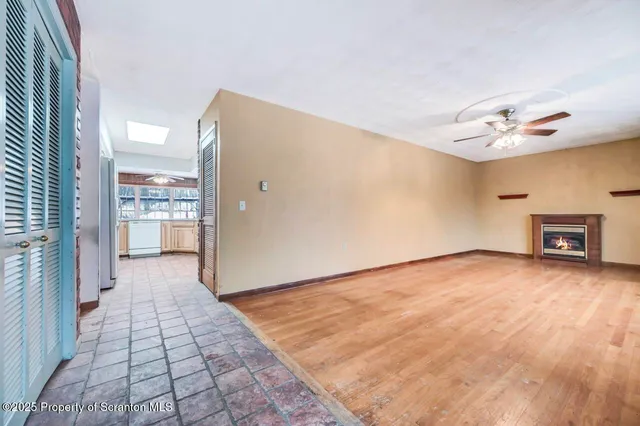 a view of an empty room with a window and wooden floor