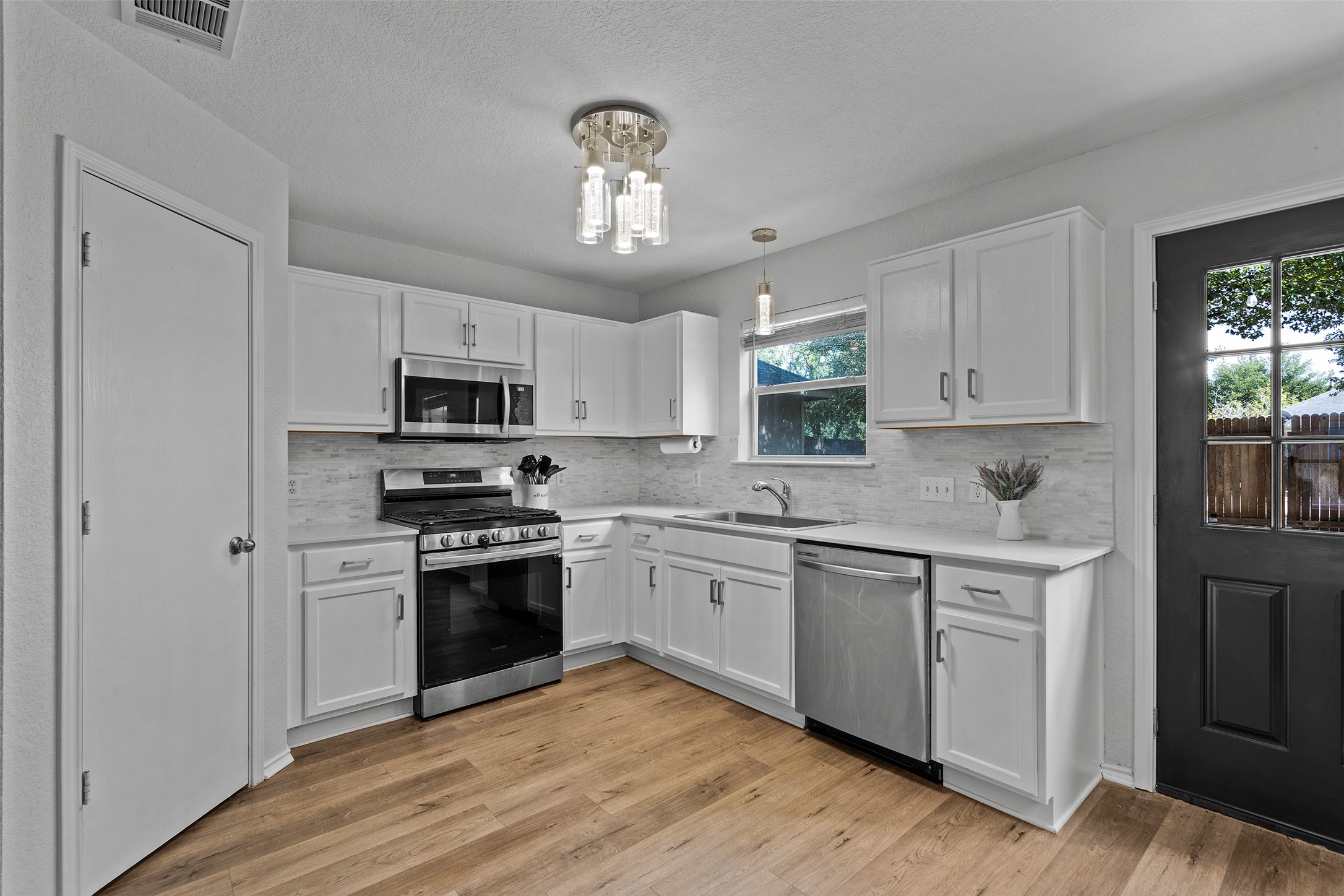 4529 Best Way Austin, TX 78725 - Photo 13 of 33 a kitchen with stainless steel appliances granite countertop a stove top oven a sink dishwasher and a refrigerator with wooden floor