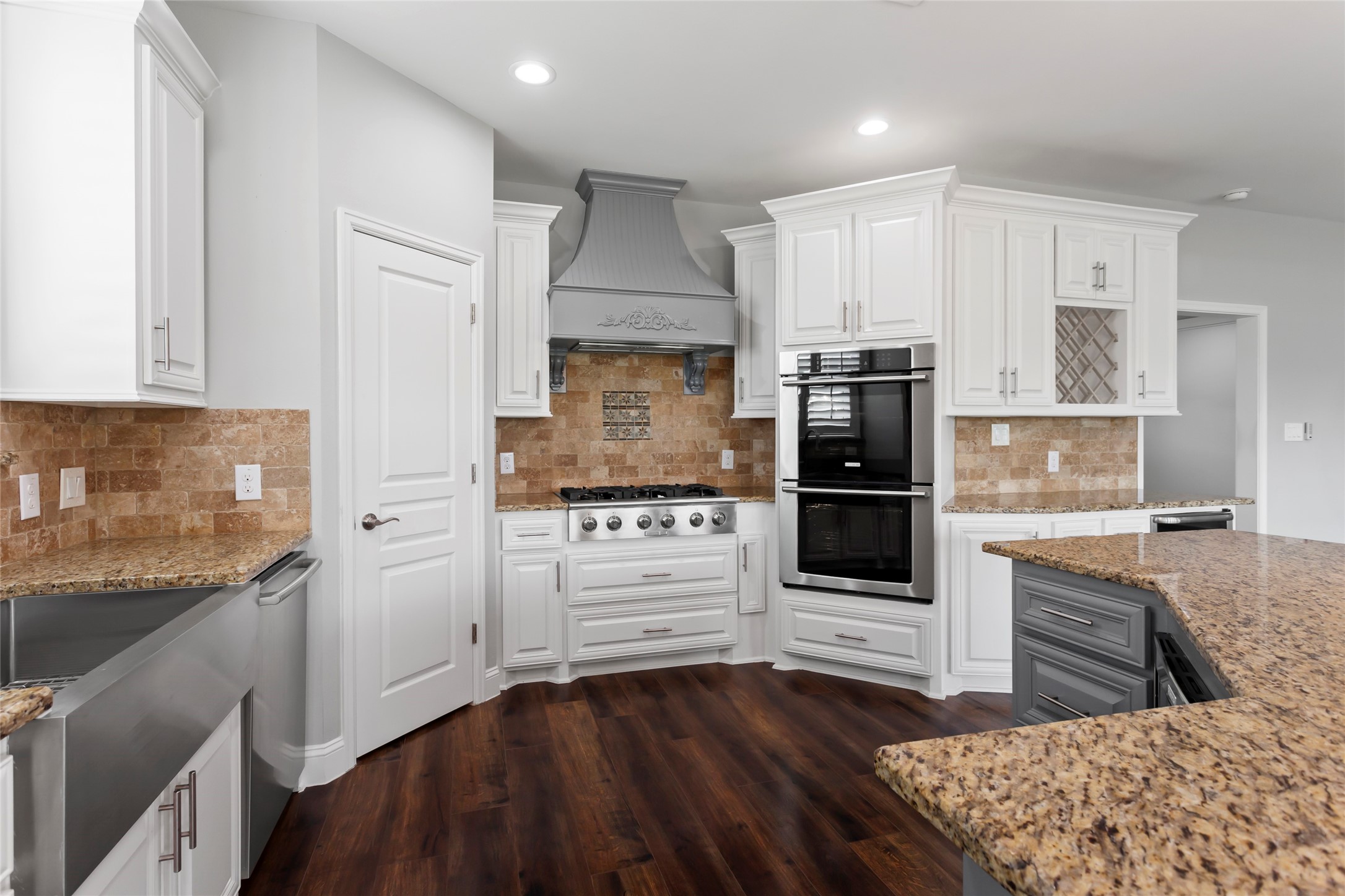 610 South Shady Lane La Porte, TX 77571 - Photo 17 of 50 This kitchen includes a stainless steel farmhouse sink, a double oven, and a gas cooktop with a decorative range hood. The space is enhanced by warm wood flooring and recessed lighting.