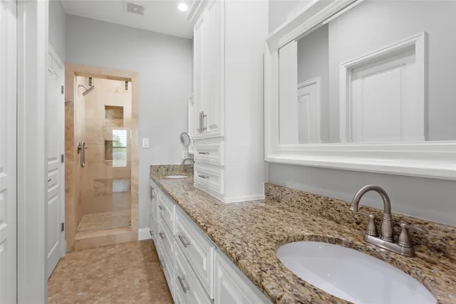 a bathroom with a granite countertop double vanity sink and mirror