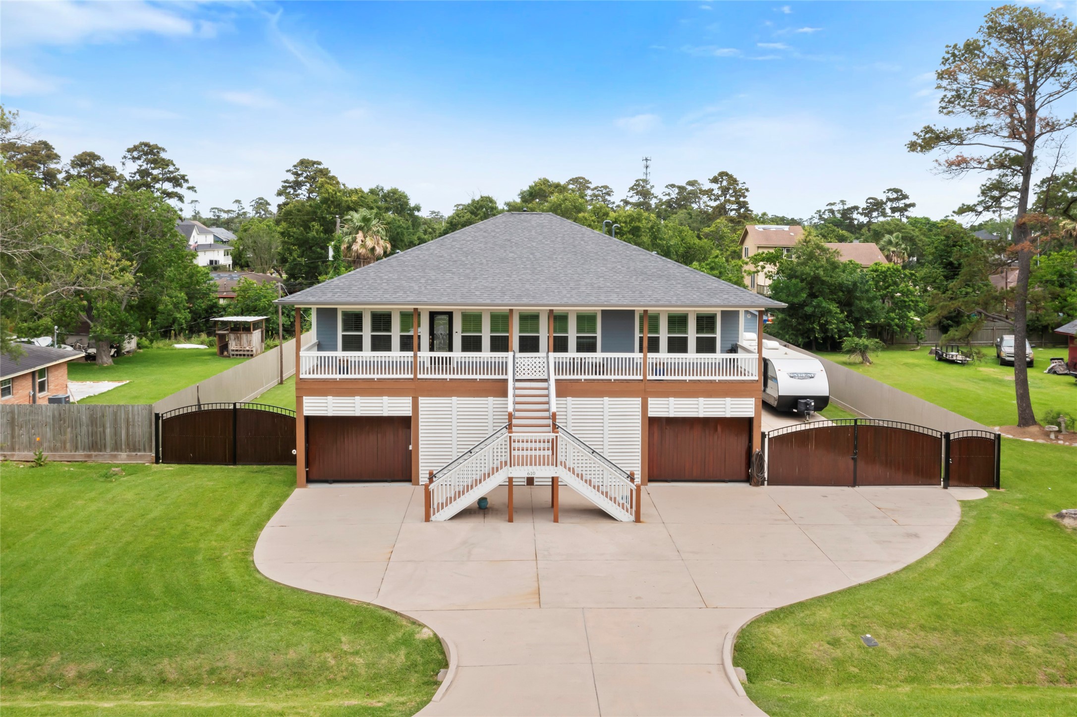 610 South Shady Lane La Porte, TX 77571 - Photo 2 of 50 This home features a spacious elevated design with a large porch and dual driveways leading to a generously-sized garage. The property is surrounded by lush greenery, providing a serene and private atmosphere.