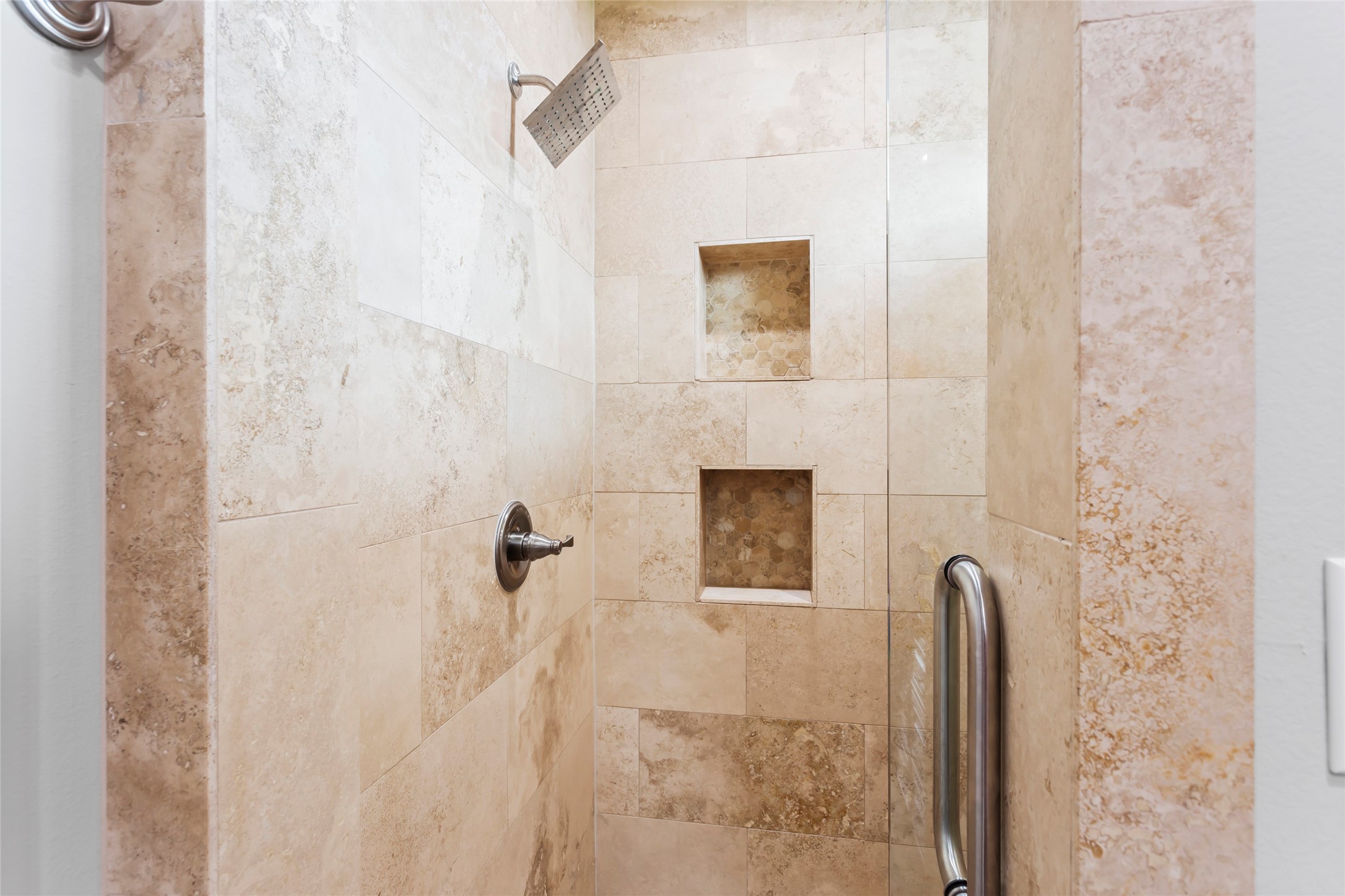 610 South Shady Lane La Porte, TX 77571 - Photo 21 of 50 This is a modern shower with elegant beige tile, featuring a rainfall showerhead and two built-in niches for storage. A sleek metal grab bar adds functionality and safety.