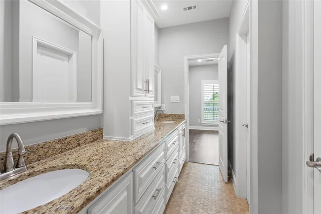 a bathroom with a granite countertop double vanity sink and a mirror