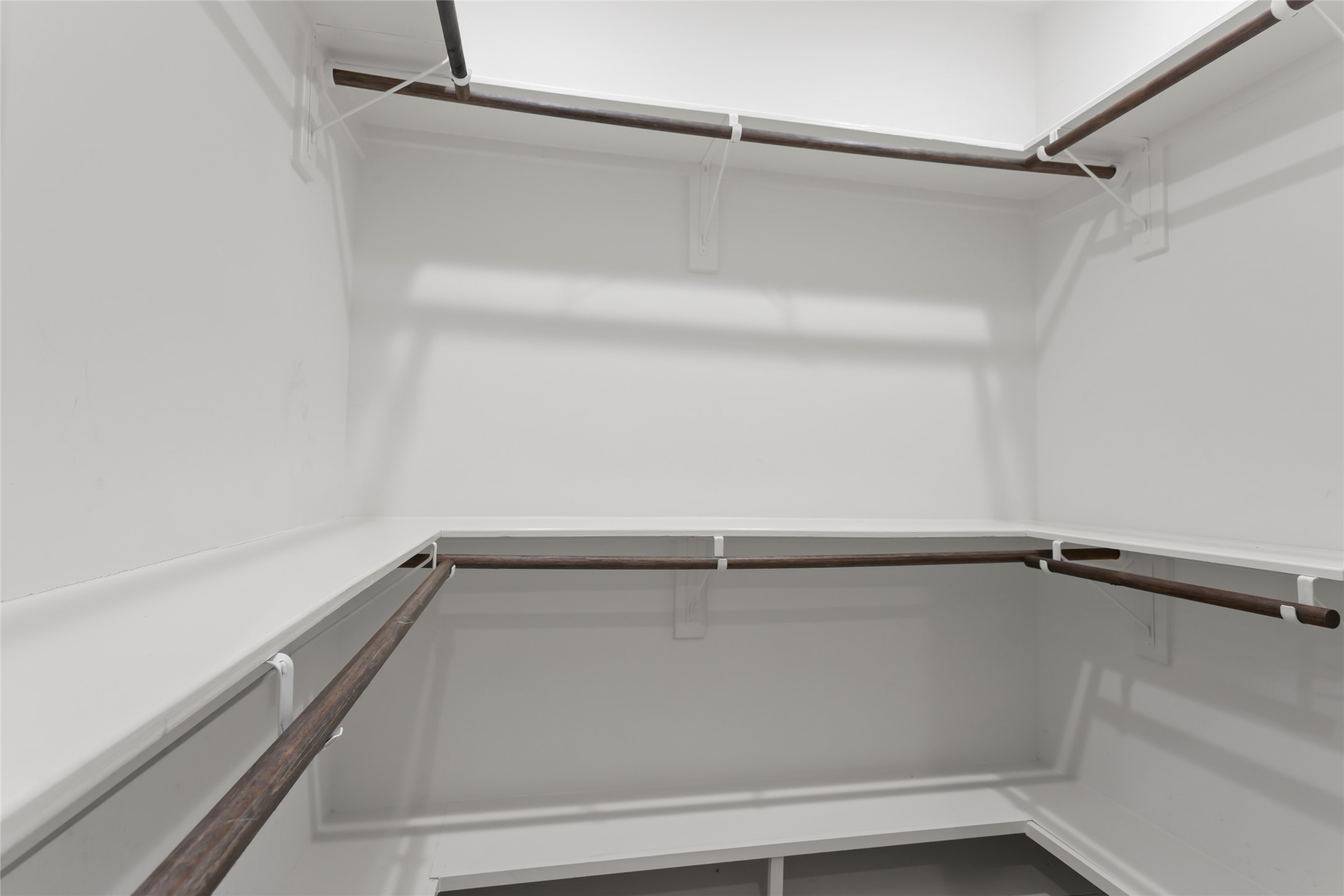 610 South Shady Lane La Porte, TX 77571 - Photo 23 of 50 Spacious walk-in closet with multiple wooden rods for hanging clothes, bright white walls, and ample shelving. Ideal for organized storage.