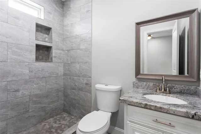 a bathroom with a granite countertop toilet sink and mirror