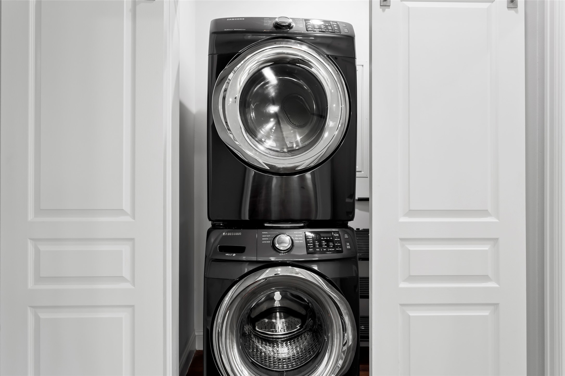 610 South Shady Lane La Porte, TX 77571 - Photo 29 of 50 A compact laundry area featuring a sleek, modern black stacked washer and dryer set, neatly enclosed within white barn doors.