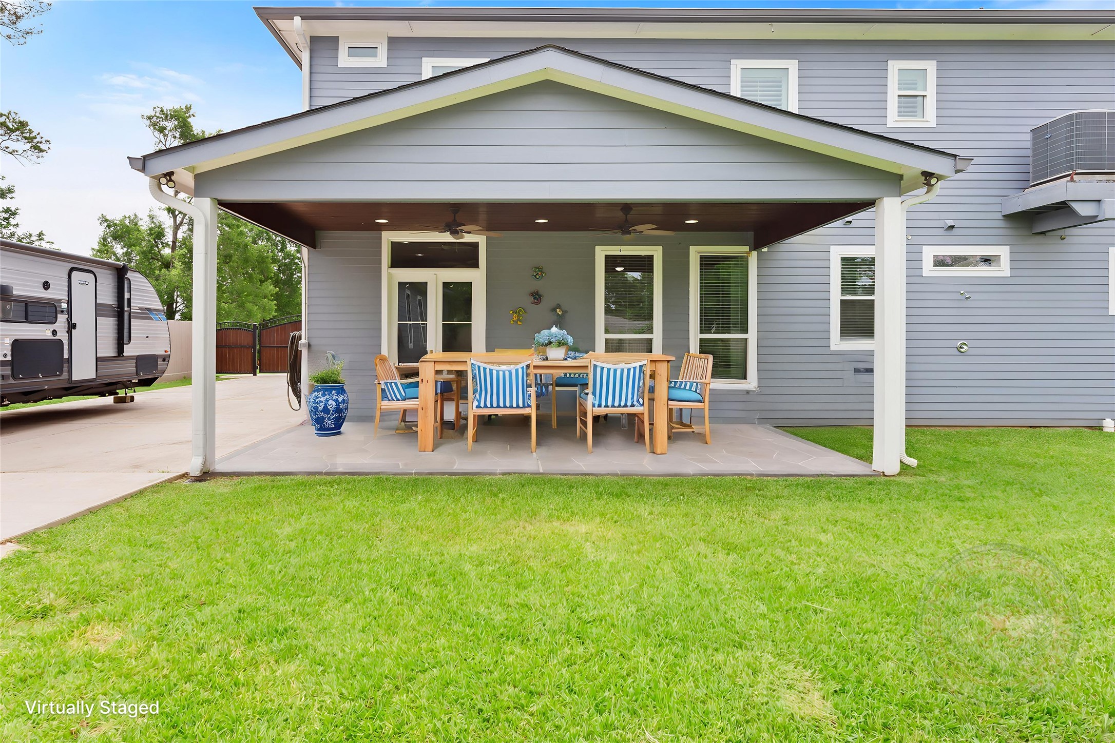 610 South Shady Lane La Porte, TX 77571 - Photo 30 of 50 This photo showcases a modern home with a spacious covered patio, perfect for outdoor dining and relaxation. The backyard features well-maintained grass and a side area for parking a trailer or RV, offering both comfort and functionality.