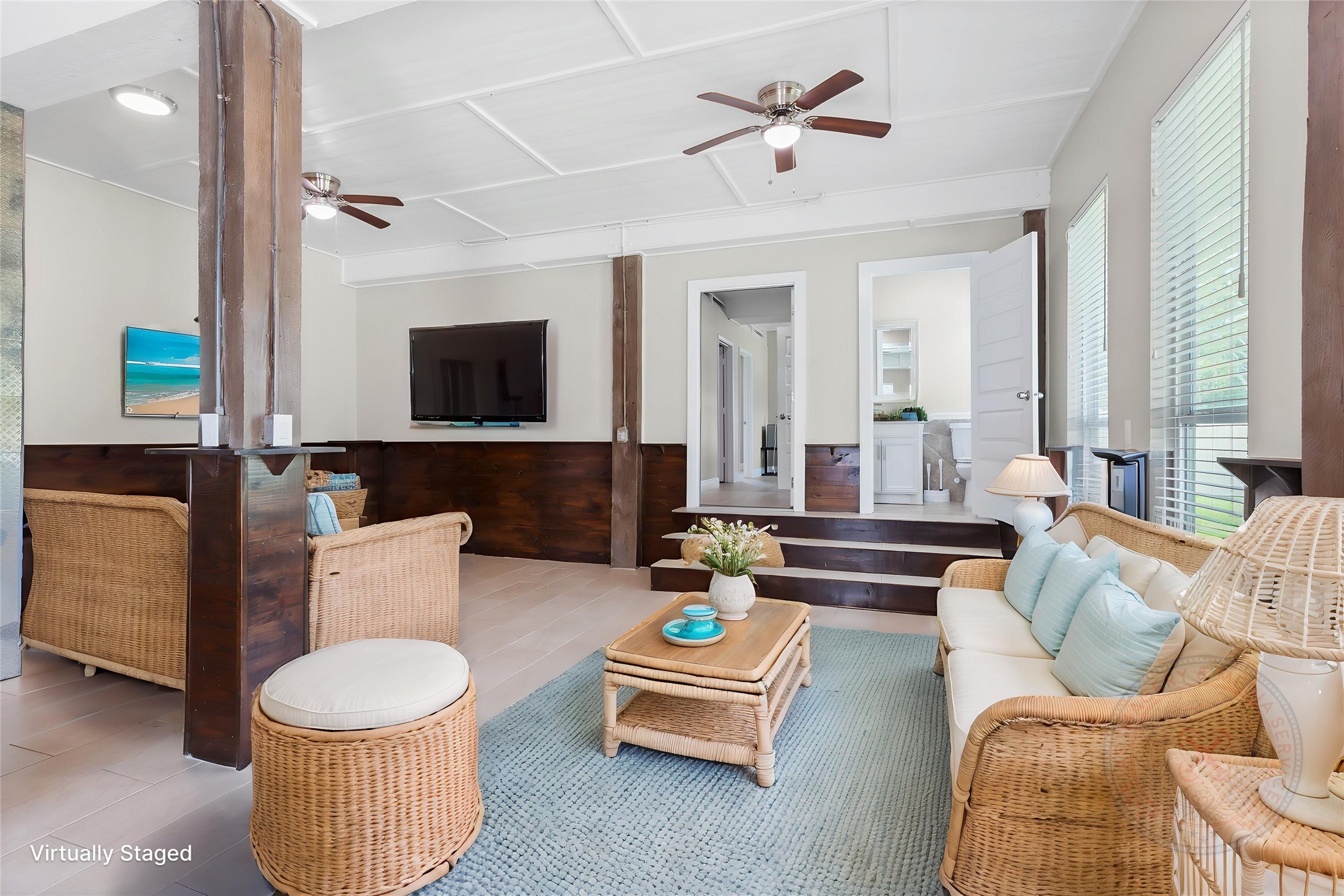 610 South Shady Lane La Porte, TX 77571 - Photo 32 of 50 This photo showcases a bright, inviting living room virtually staged with a neutral color palette. There are large windows for natural light, ceiling fans, and a space for a wall-mounted TV.