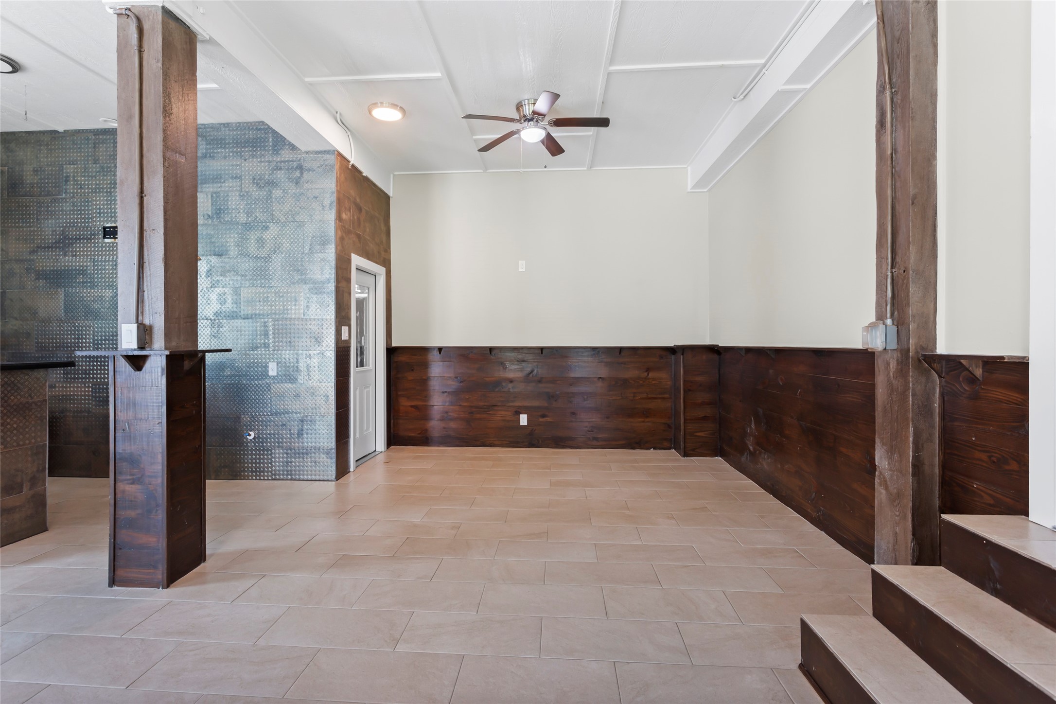 610 South Shady Lane La Porte, TX 77571 - Photo 33 of 50 This room features a modern, open layout with light tile flooring and rustic wooden accents. It has high ceilings, a ceiling fan, and a blend of textured and smooth walls. Ideal for a cozy living space.