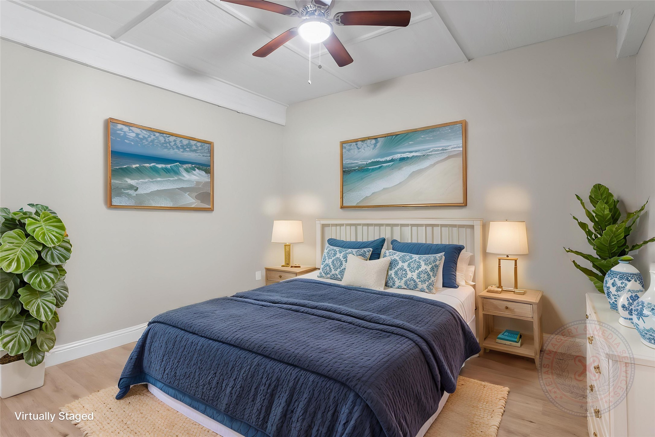 610 South Shady Lane La Porte, TX 77571 - Photo 42 of 50 This virtually staged bedroom features a cozy, tranquil ambiance with a neutral color palette. It has a double bed with blue and white bedding, two bedside tables with lamps, and coastal-themed artwork. The room is accented with plants and a ceiling fan, creating a relaxing retreat.