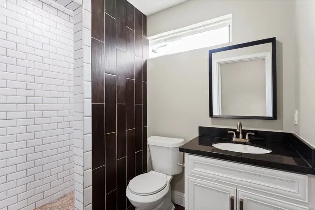 a bathroom with a granite countertop sink toilet a mirror and shower