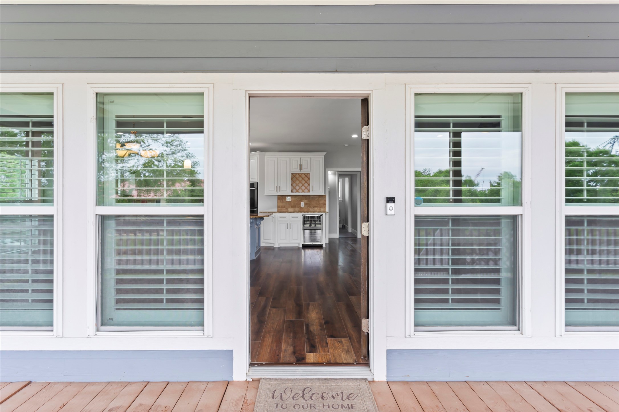 610 South Shady Lane La Porte, TX 77571 - Photo 10 of 50 This photo showcases a welcoming entryway with large windows featuring plantation shutters, leading into a bright, open-concept kitchen and living space with wood laminate floors.