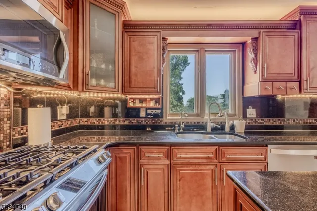 a kitchen with stainless steel appliances granite countertop a stove a sink and a microwave