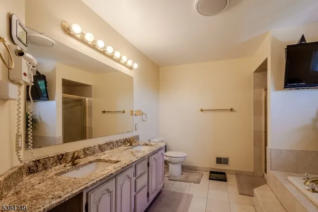 a spacious bathroom with a double vanity sink a mirror and a toilet