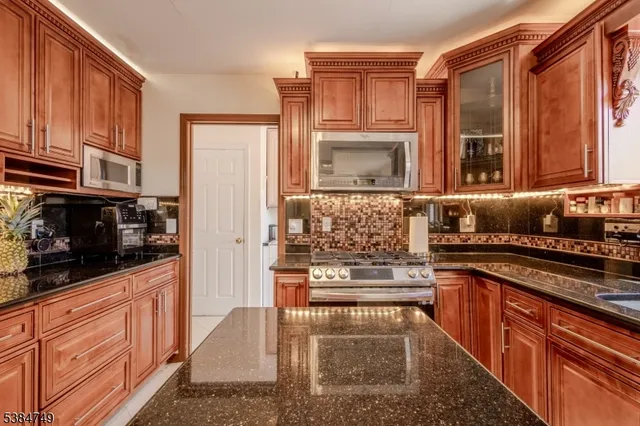 a kitchen with stainless steel appliances granite countertop a stove a sink and a microwave