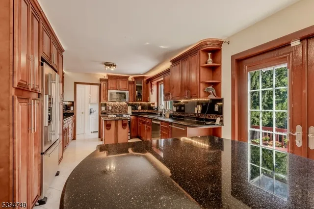 a kitchen with stainless steel appliances granite countertop a refrigerator a stove and a sink with wooden floor
