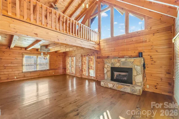 a view of an empty room with wooden floor and fireplace