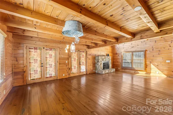 a view of an empty room with wooden floor and windows