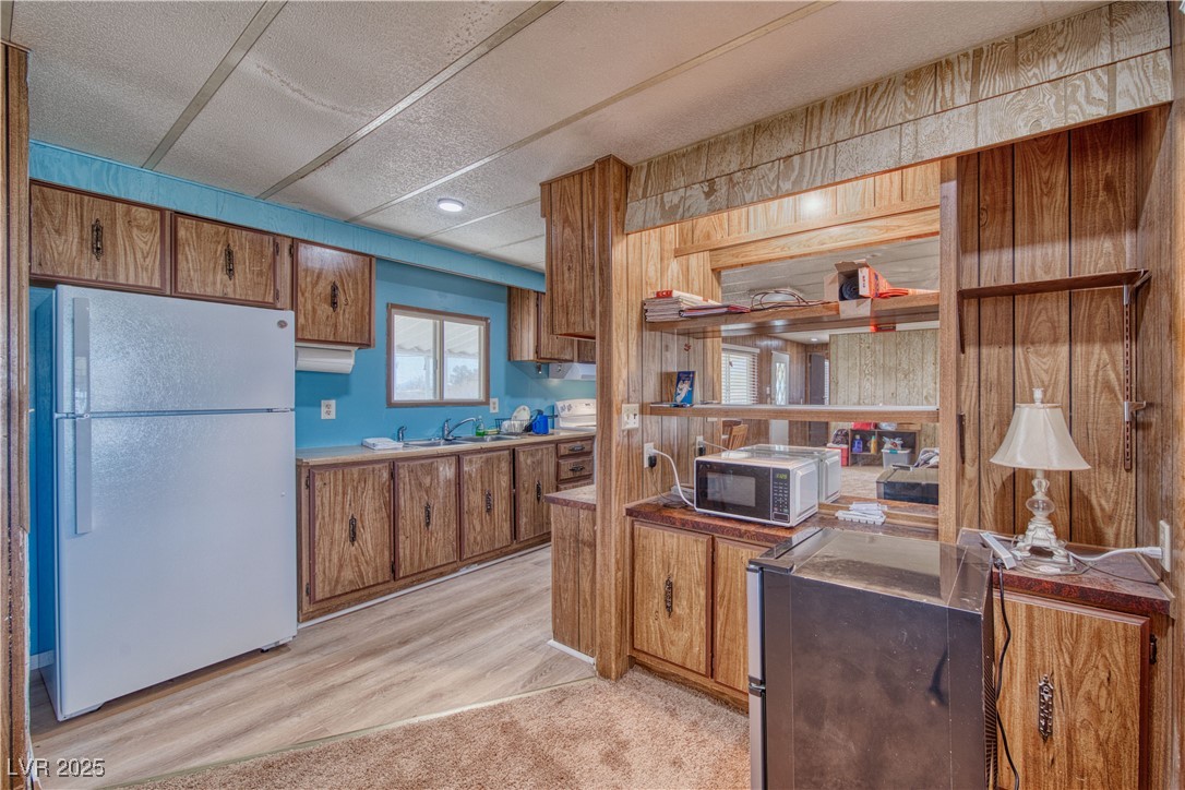 2631 Retread Road Pahrump, NV 89048 - Photo 16 of 18 Kitchen featuring a textured ceiling, brown cabinets, freestanding refrigerator, and a sink