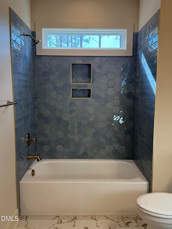 a bathroom with a sink a toilet a mirror a bathtub and shower