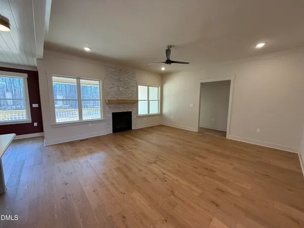 an empty room with windows and fireplace