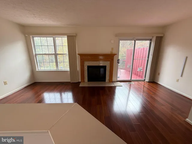 an empty room with wooden floor fireplace and windows