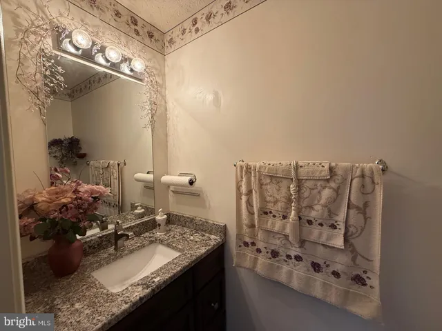 a bathroom with a granite countertop sink a mirror and shower