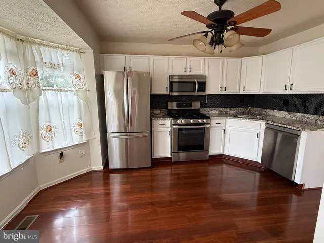 a kitchen with stainless steel appliances a stove a refrigerator and white cabinets