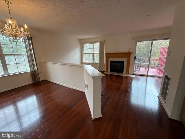 wooden floor in an empty room with a fireplace and a window