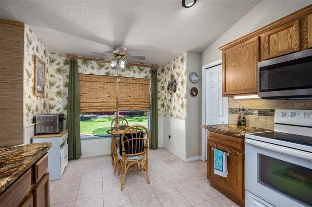 a kitchen with stainless steel appliances granite countertop a stove top oven a sink dishwasher a dining table and chairs with wooden floor