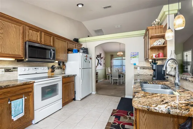 a kitchen with stainless steel appliances kitchen island granite countertop a stove top oven a sink dishwasher and a fireplace with wooden floor